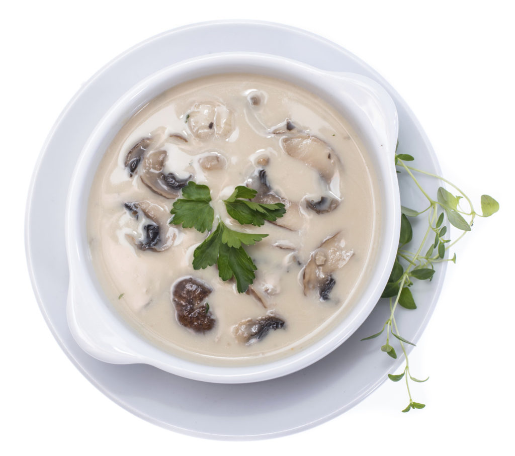 Fresh Mushroom Soup topped with some herbs isolated on white background