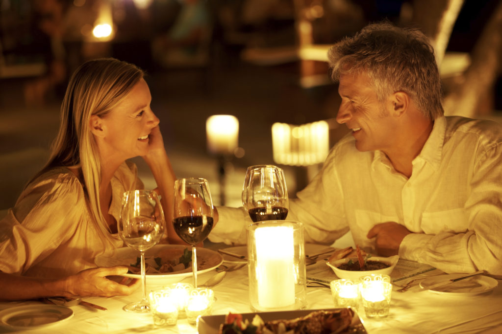 Middle aged couple enjoying a romantic candlelight dinner at restaurant